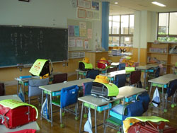 1年2組の教室　（椅子の背にかけてあるのは、防災頭巾）